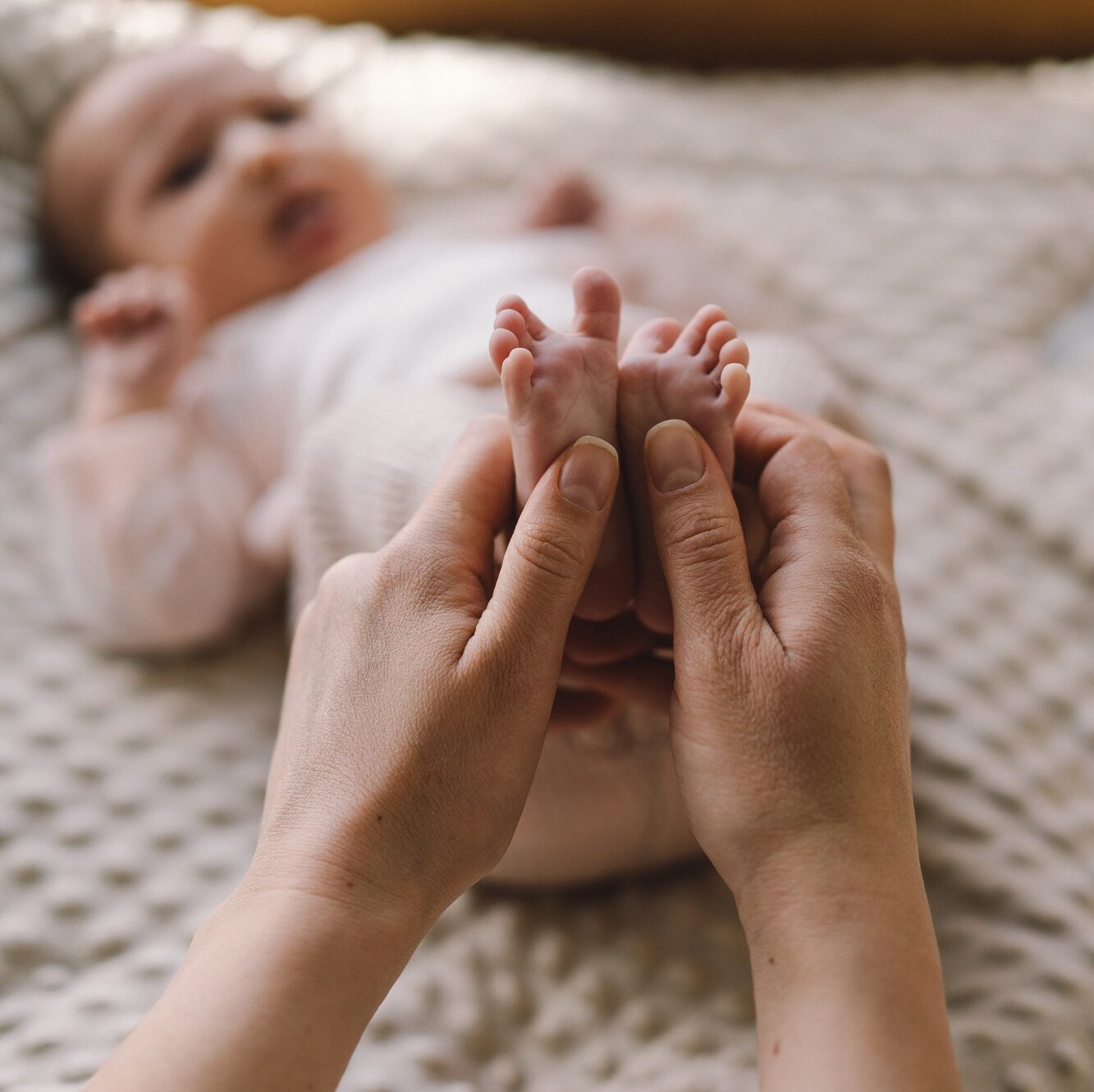Mum making baby massage, mother massaging infant bare foot